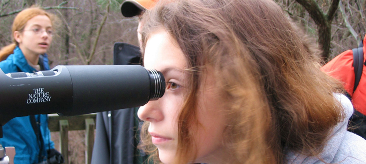 girl looking through telescope